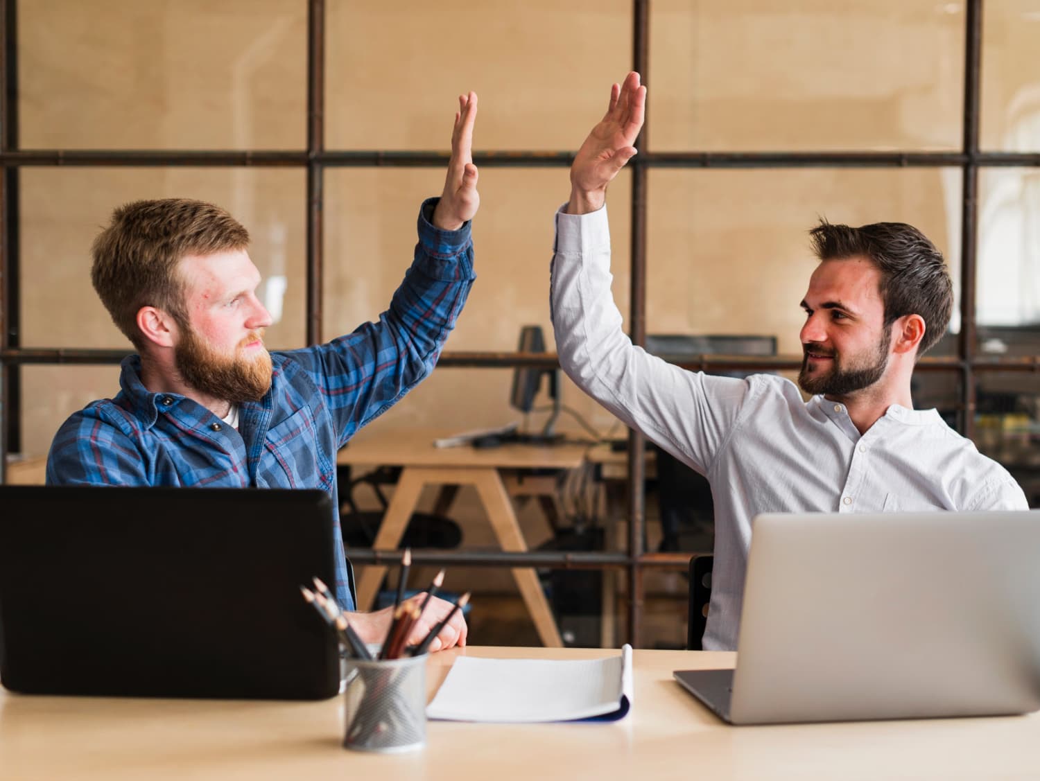 Two professionals celebrating success with and enthusiastic high five.